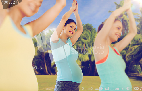 Image of happy pregnant women exercising outdoors