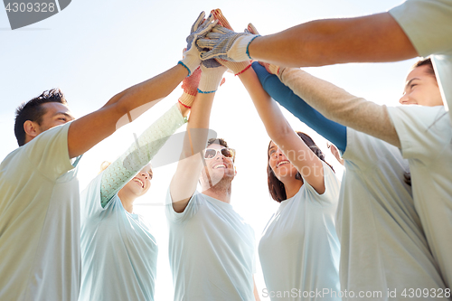 Image of group of volunteers making high five outdoors