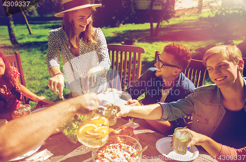 Image of happy friends having dinner at summer garden party