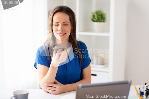 Image of woman using voice recorder on smartphone at office