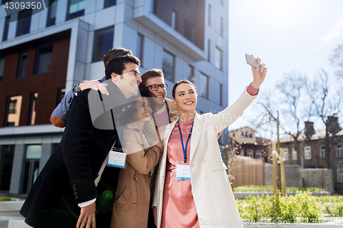 Image of happy people with conference badges taking selfie