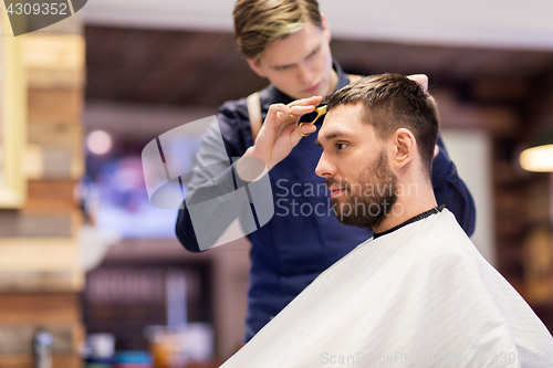 Image of man and barber cutting hair at barbershop
