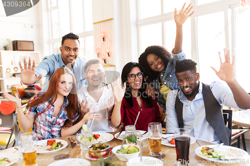 Image of happy friends eating at restaurant