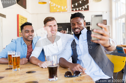 Image of friends taking selfie and drinking beer at bar