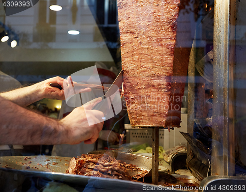 Image of An arm moving to cut the kebab meat