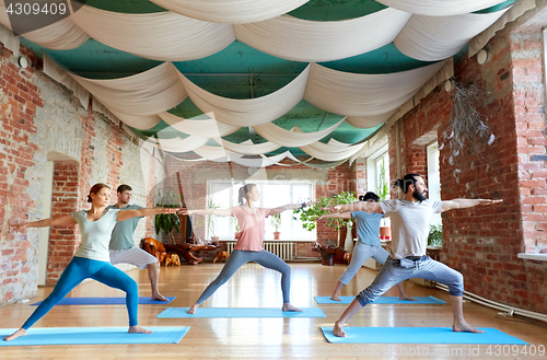 Image of group of people doing yoga warrior pose at studio