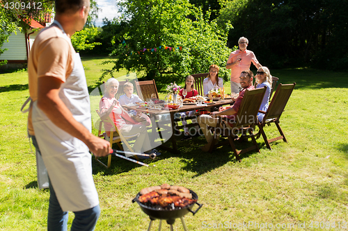 Image of man cooking meat on barbecue grill at summer party