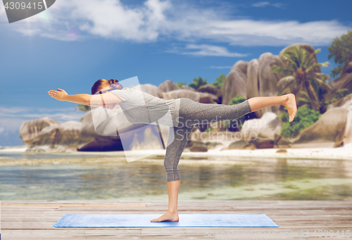 Image of woman doing yoga warrior pose on half-bent outdoor