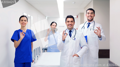 Image of happy doctors with gurney showing ok at hospital