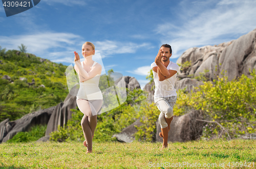 Image of smiling couple making yoga exercises outdoors