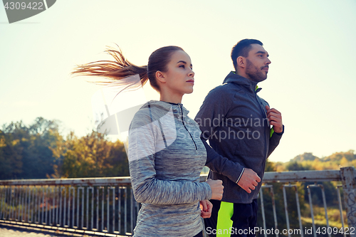 Image of happy couple running outdoors