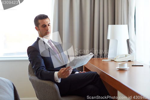 Image of businessman reading newspaper at hotel room