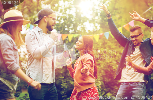 Image of happy friends dancing at summer party in garden