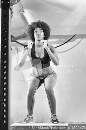 Image of black female athlete is performing box jumps at gym