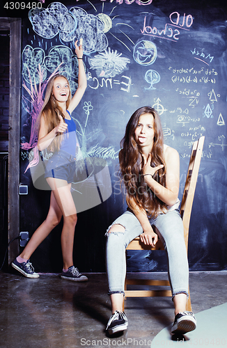 Image of back to school after summer vacations, two teen girls in classroom with blackboard painted