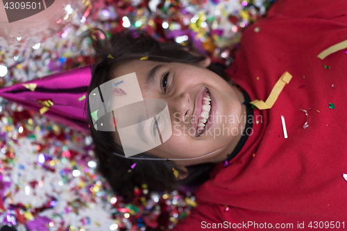 Image of kid blowing confetti while lying on the floor