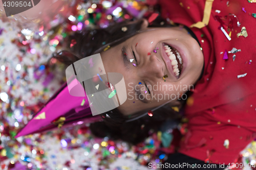 Image of kid blowing confetti while lying on the floor