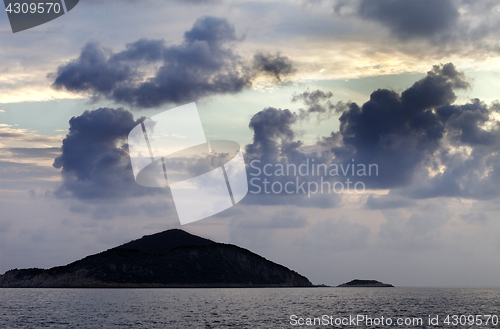 Image of Island in sea and sky with dark clouds at sunset