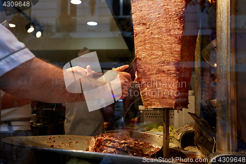 Image of An arm moving to cut the kebab meat