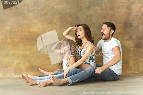 Image of Pregnant mother with teen daughter and husband. Family studio portrait over brown background