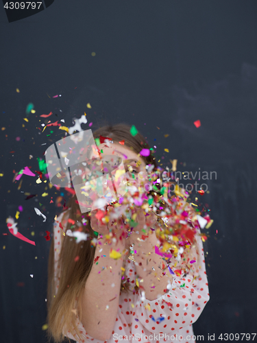 Image of woman blowing confetti in the air isolated over gray