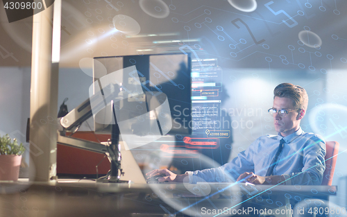 Image of man working on computer in dark office