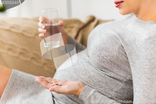 Image of close up of pregnant woman with pills at home