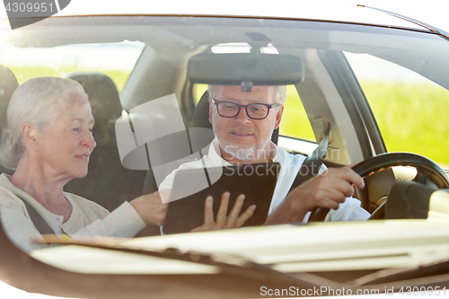 Image of happy senior couple with tablet pc driving in car