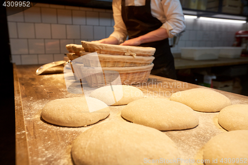 Image of baker with baskets for dough rising at bakery