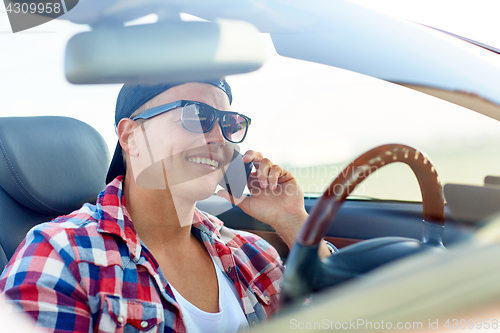 Image of young man driving car and calling on smartphone