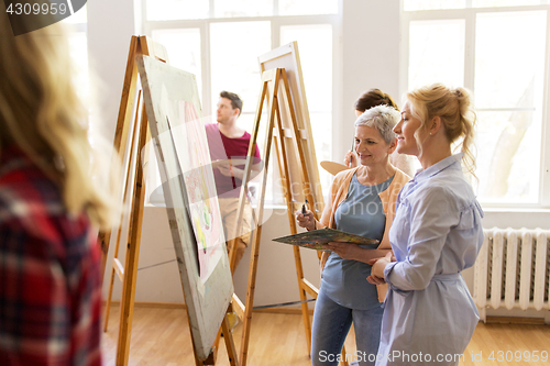 Image of artists discussing painting on easel at art school