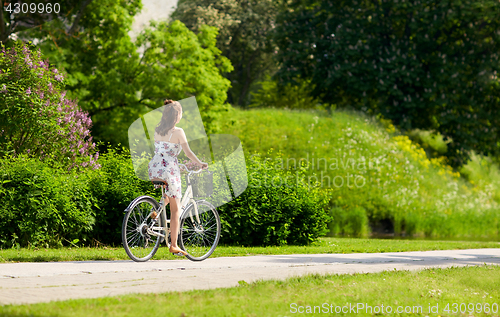 Image of happy woman riding fixie bicycle in summer park