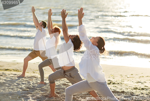 Image of group of people making yoga exercises on beach