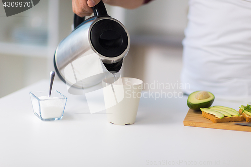 Image of man with kettle making tea for breakfast at home