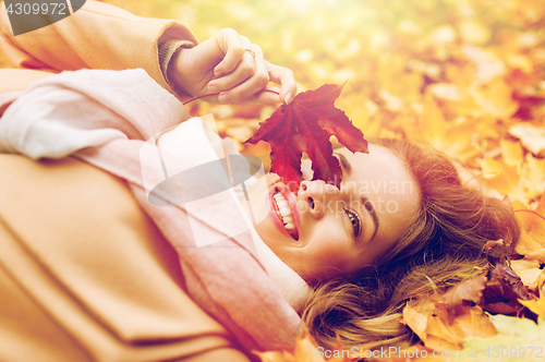 Image of beautiful happy woman lying on autumn leaves