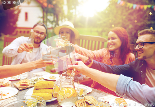 Image of happy friends with drinks at summer garden party