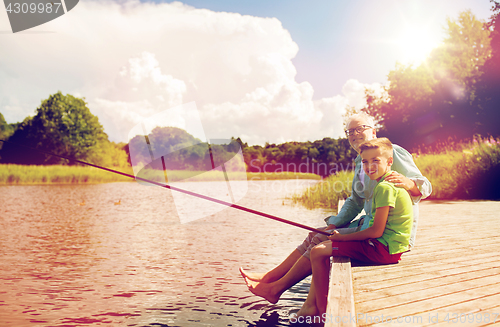 Image of grandfather and grandson fishing on river berth