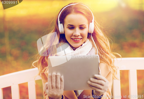 Image of woman with tablet pc and headphones in autumn park