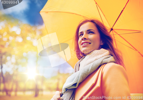 Image of happy woman with umbrella walking in autumn park