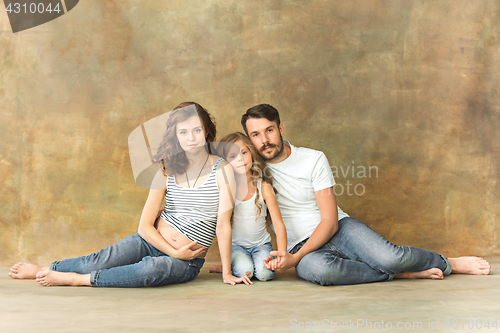 Image of Pregnant mother with teen daughter and husband. Family studio portrait over brown background