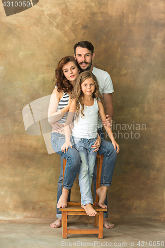 Image of Pregnant mother with teen daughter and husband. Family studio portrait over brown background