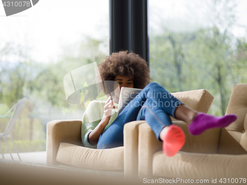 Image of young african american woman at home using digital tablet