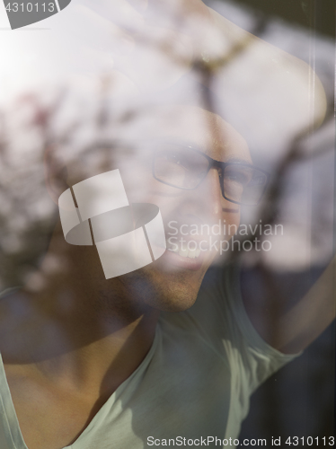 Image of young man drinking morning coffee by the window