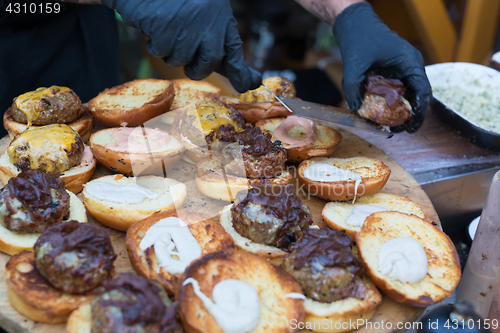 Image of Chef making beef burgers outdoor on open kitchen international food festival event.