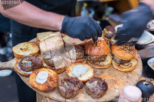 Image of Chef making beef burgers outdoor on open kitchen international food festival event.