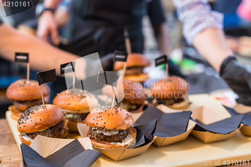 Image of Chef making beef burgers outdoor on open kitchen international food festival event.