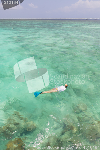 Image of Woman snorkeling in clear shallow sea of tropical lagoon with turquoise blue water.