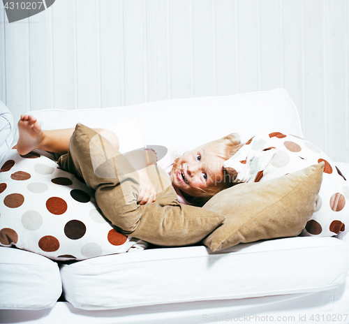 Image of little cute blonde girl playing at home with pillows