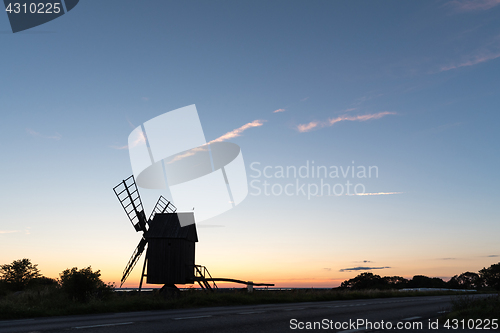 Image of Wooden windmill silhouette by roadside