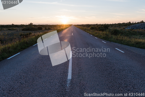 Image of Straight country road by sunset in an open landscape